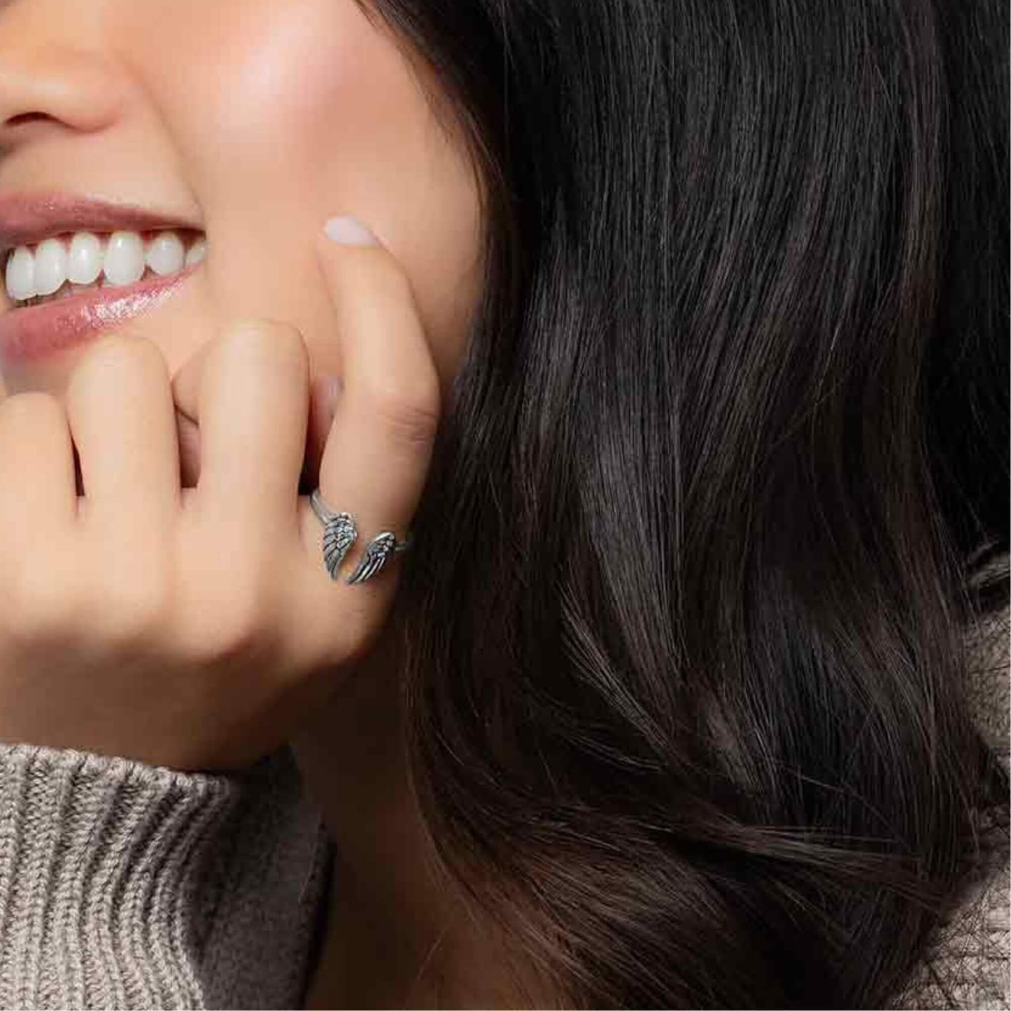 Women hand model wearing our small sterling silver adjustable angel wing ring.
