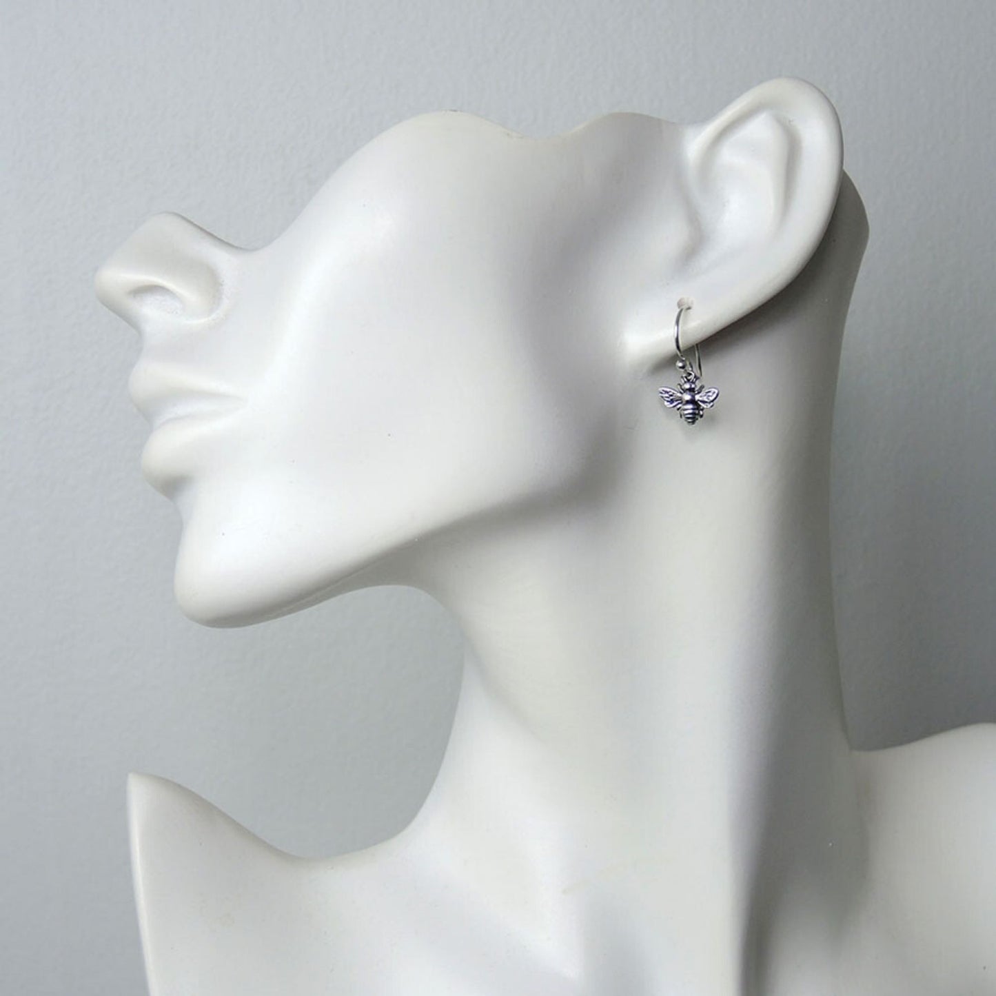Model of a woman wearing petite silver bee dangle earrings.