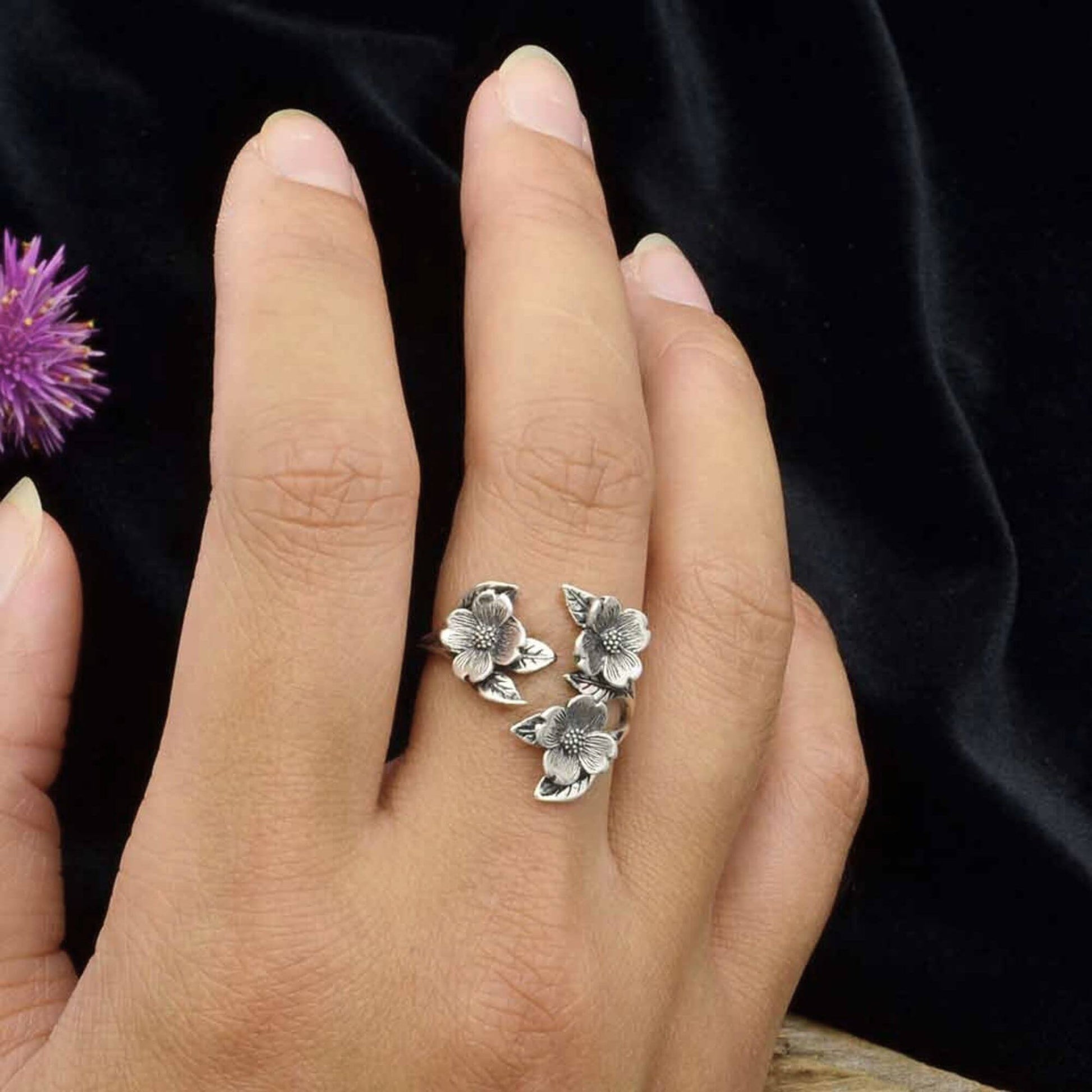 CLose up of a womans hand wearing the dogwood flower ring that is a statement ring that is beautiful and would make the perfect gift for garden lovers.