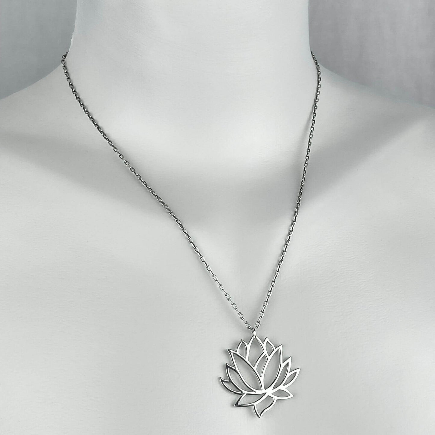 A woman wearing a sterling silver chain necklace with a trendy large lotus pendant.