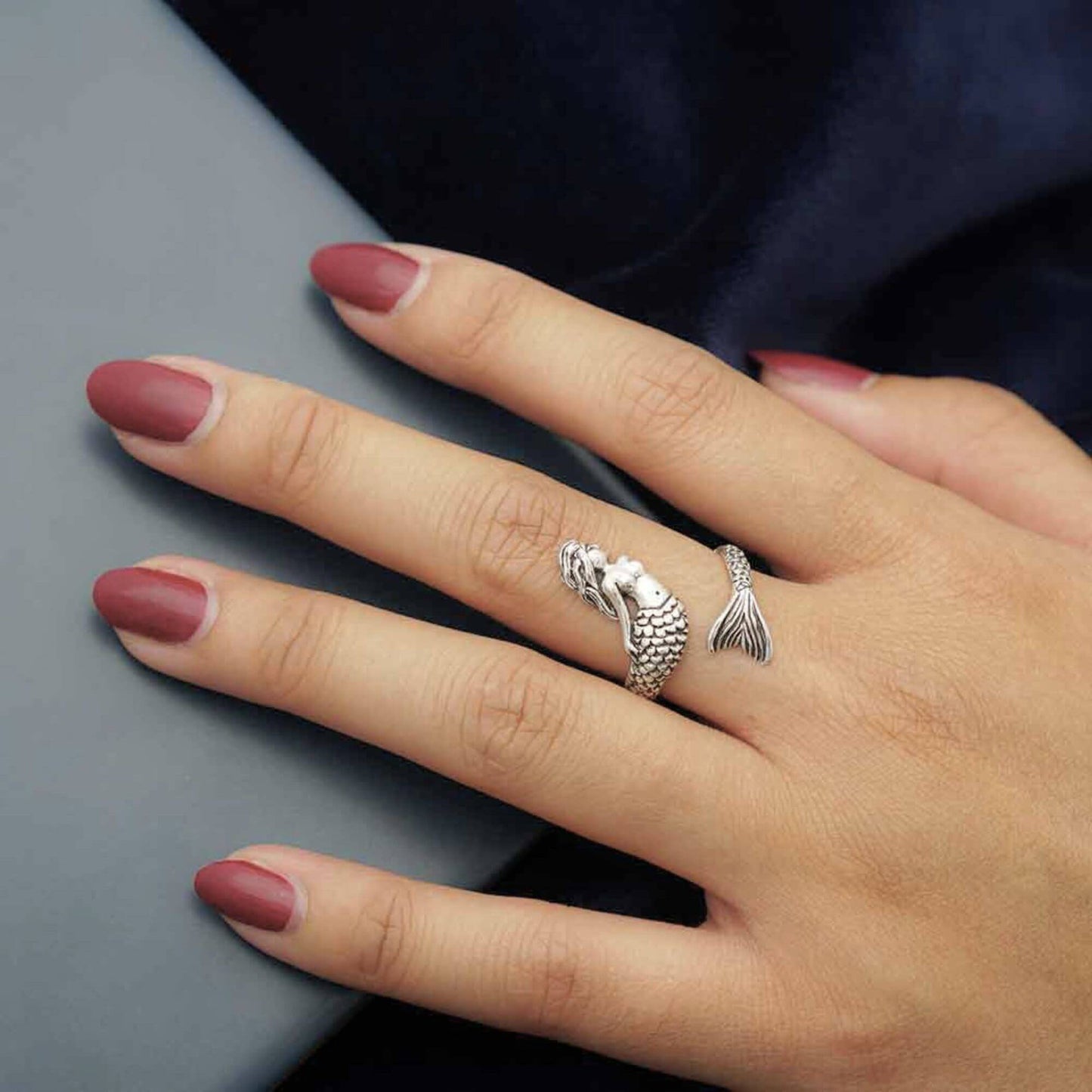 Hand model showing a adjustable mermaid ring wrapping around the finger that is about 1" from the mermaid head to the end of the mermaid tail. Womans Ring is adjustable.