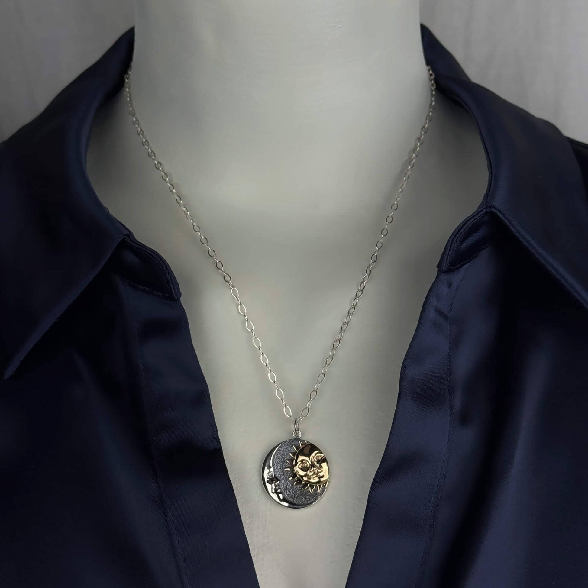 A woman wearing a sterling silver chain necklace with a trendy moon and sun in a round coin with gold and silver  pendant.