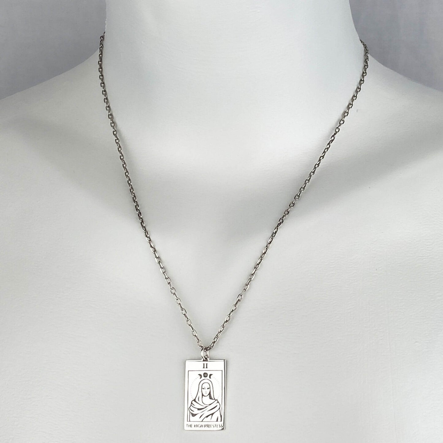 A woman wearing a sterling silver chain necklace with a trendy tarot card goddess pendant.