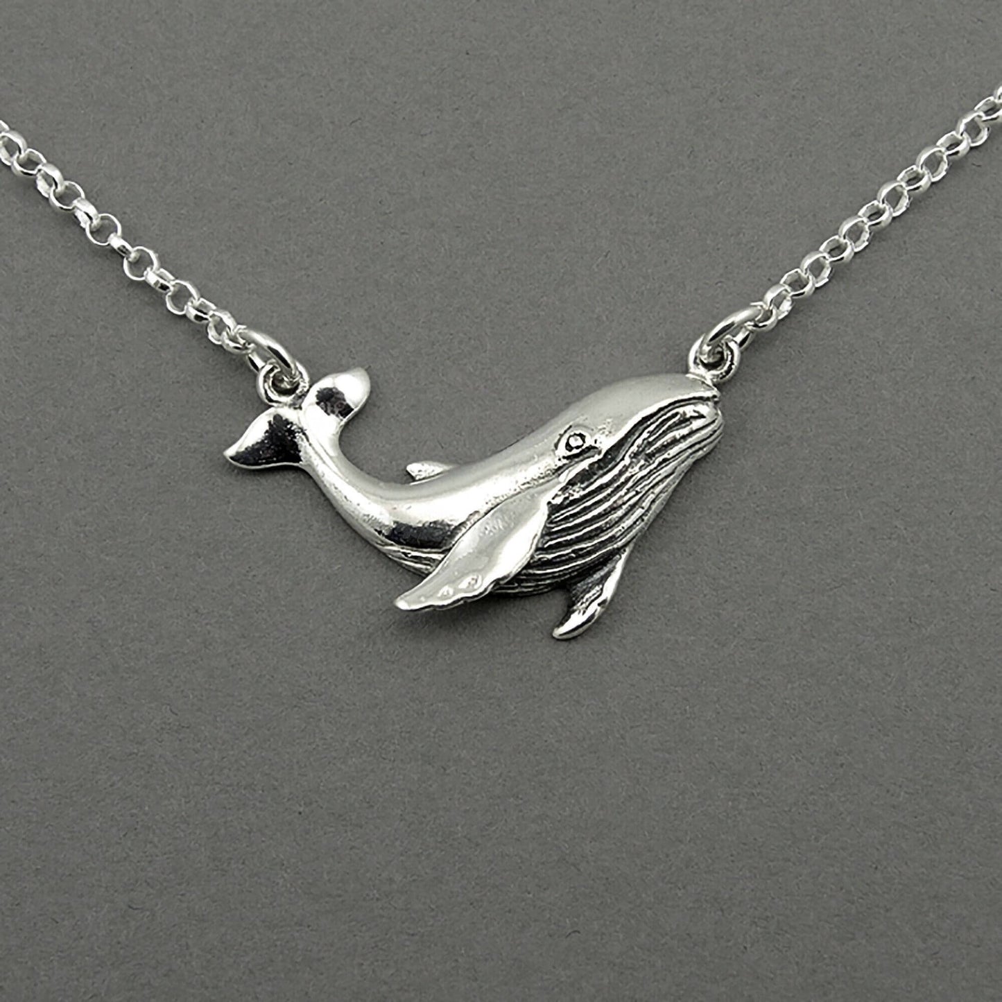 Sterling silver humpback whale pendant floating on the silver chain. The whale is detailed.