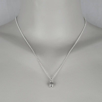 A woman wearing a sterling silver chain necklace with a trendy petite  small acorn charm.