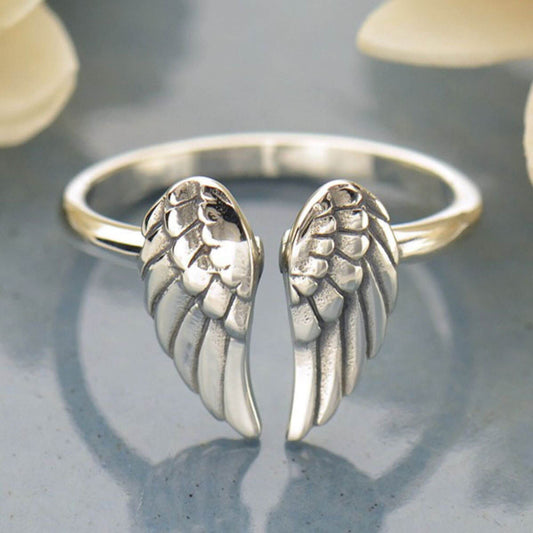 Close up showing a shiny silver double wings at both ends of the adjustable ring band.  The double angel wings are slightly oxidized to add feathering detail. 