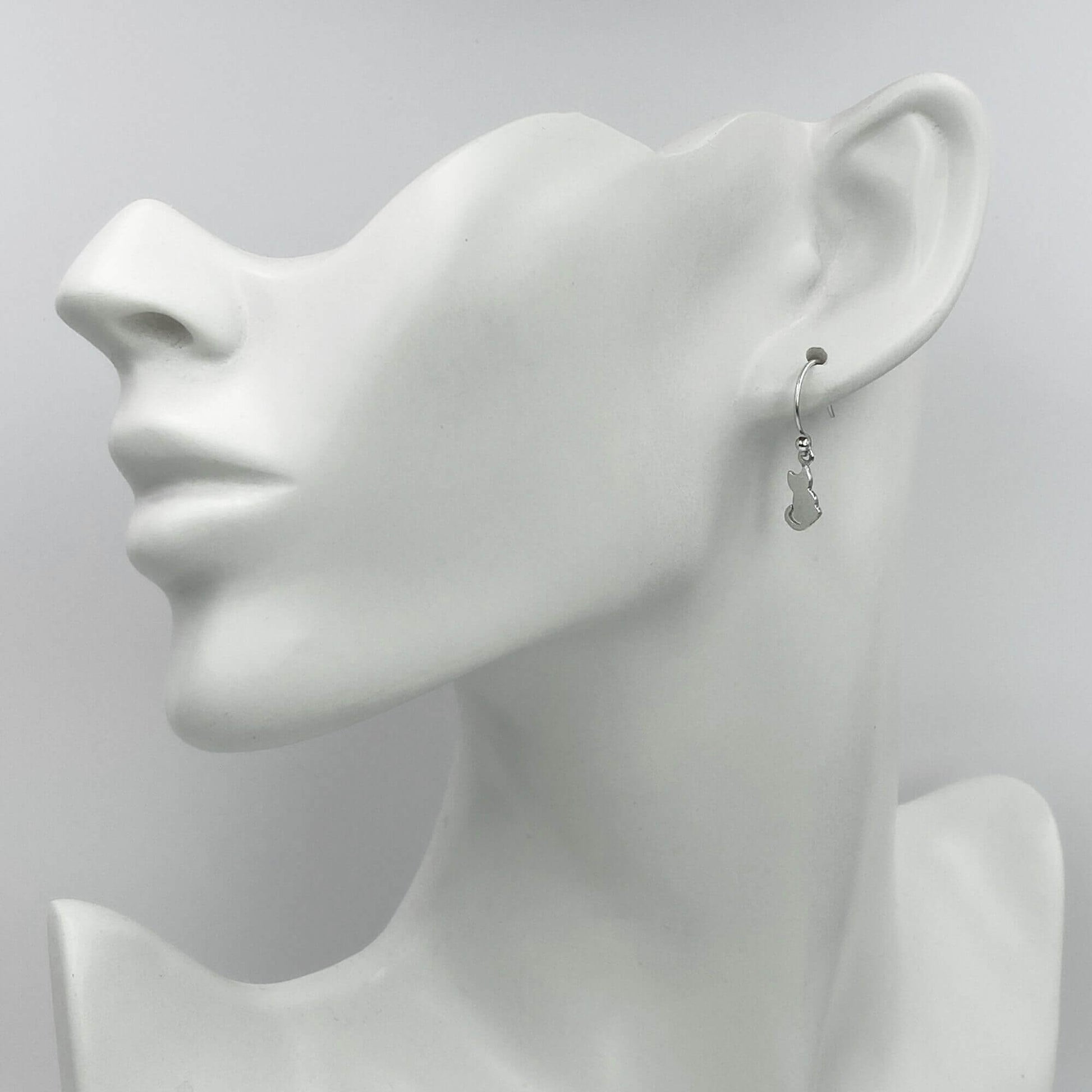 Model of a woman wearing petite silver cat silhouette dangle earrings.