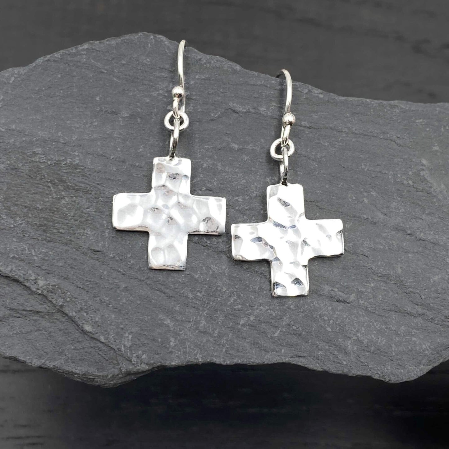 Detailed view of silver delicate earrings with a spiritually inspired 2D cross design.