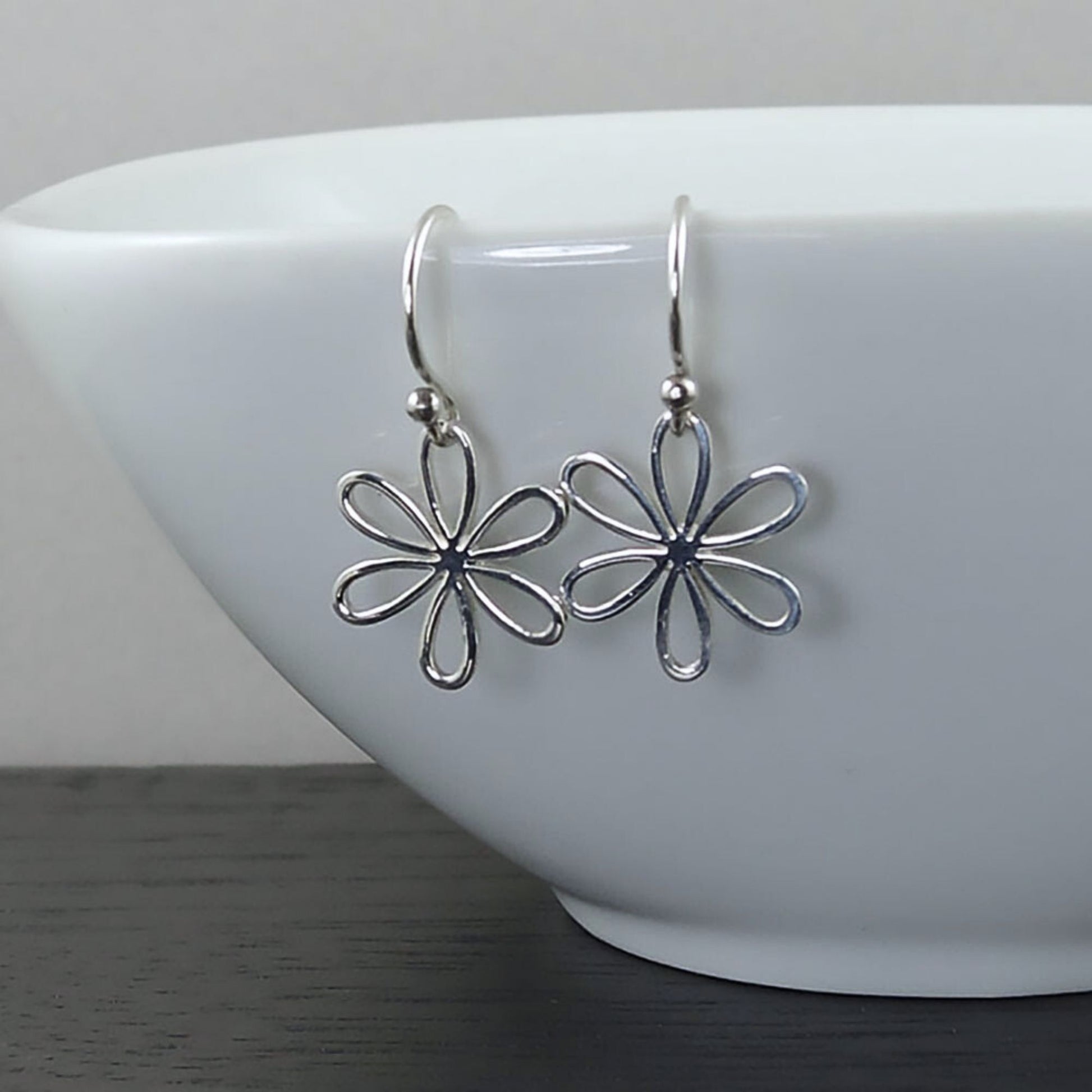 Detailed view of dainty silver earrings with a minimalist daisy design.