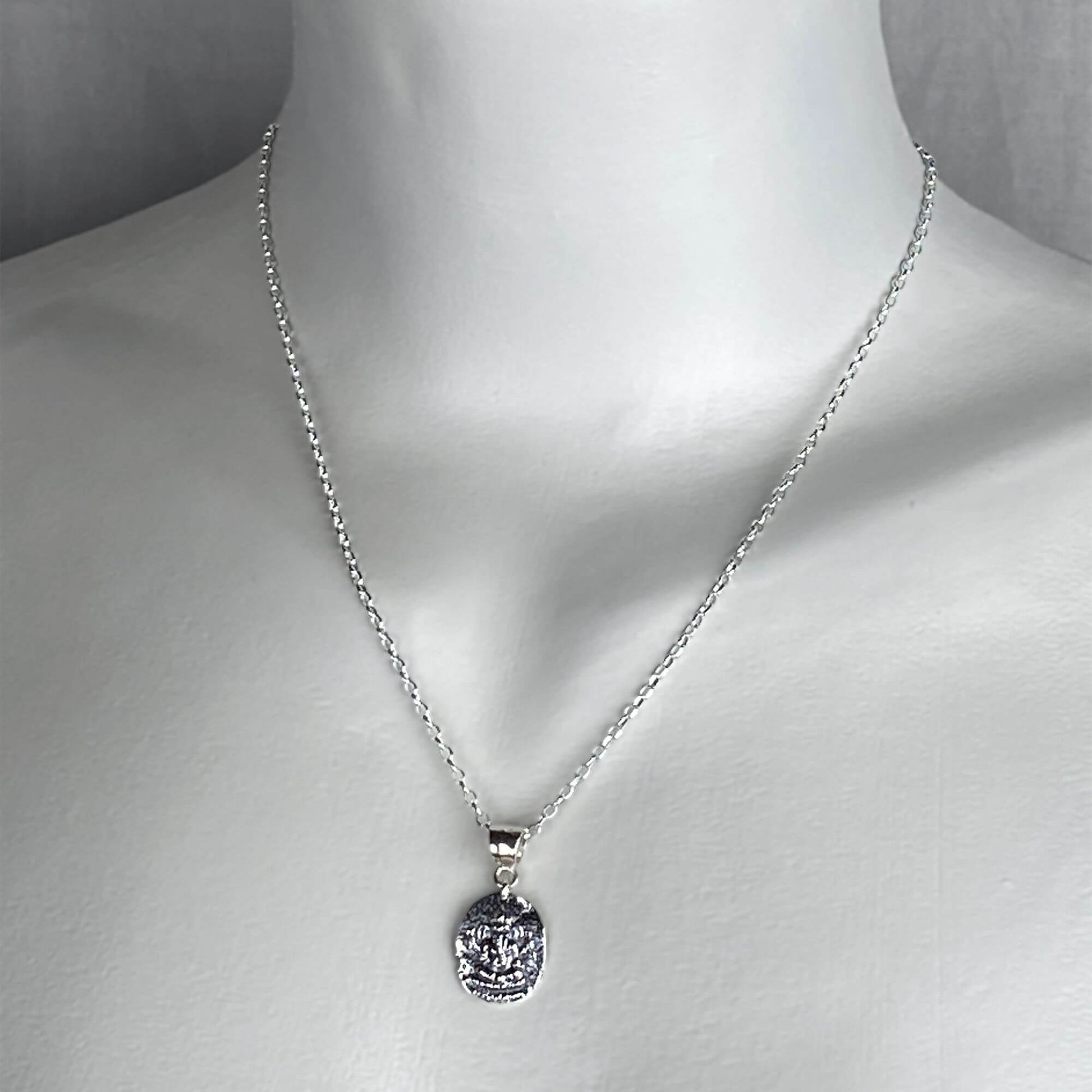 A woman wearing a sterling silver chain necklace with a hindu Ganesh god  pendant charm on a silver chain.