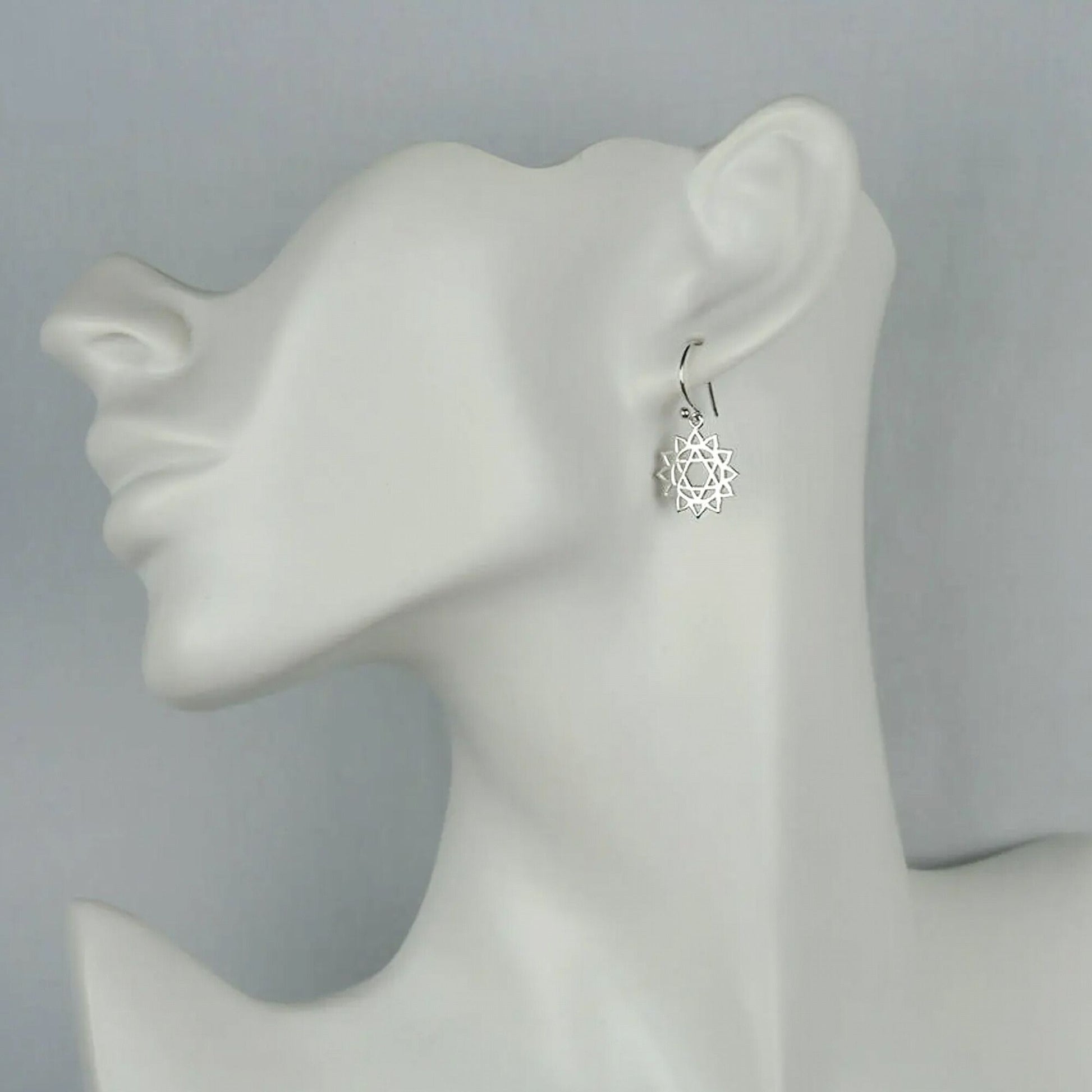 Model of a woman wearing small silver spiritually-inspired heart chakra dangle earrings.