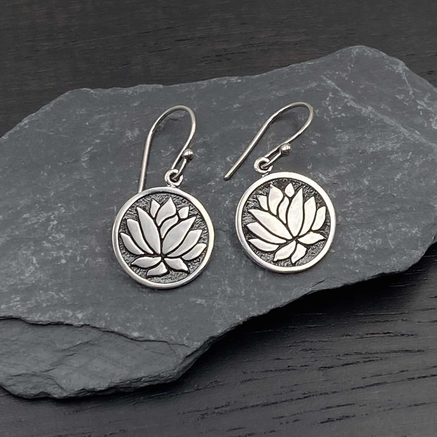 Detailed view of silver feminine earrings with a circular lotus design.