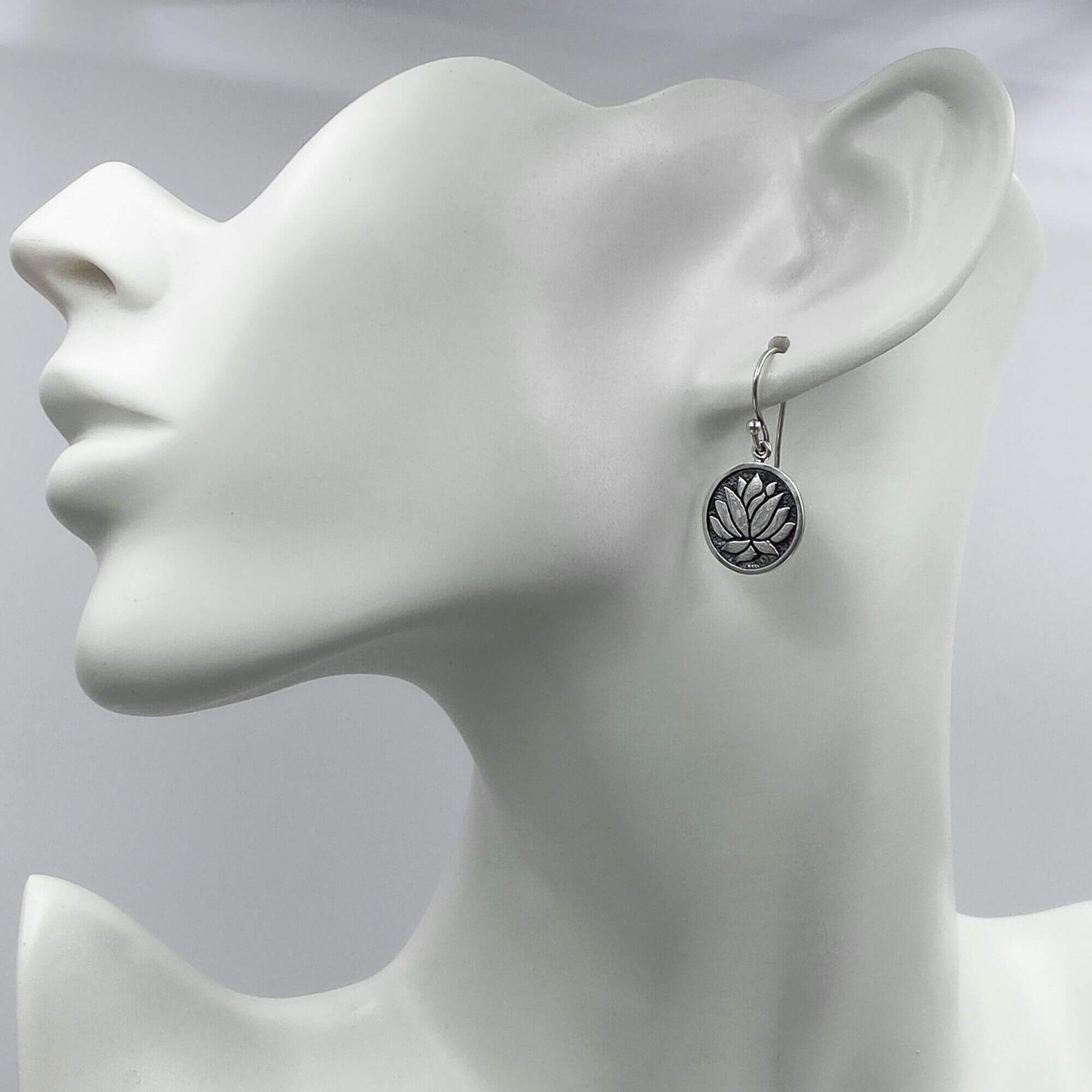 Model of a woman wearing small elegant silver lotus dangle earrings.