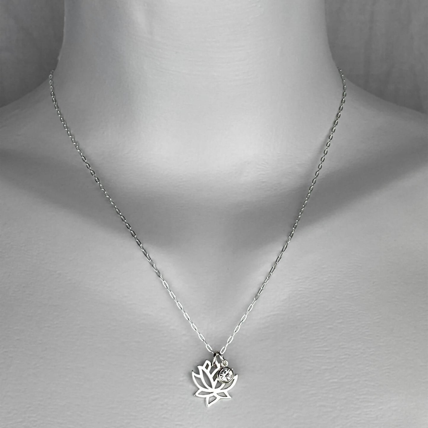 A woman wearing a sterling silver chain necklace with a trendy lotus and crystal  small charm.