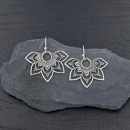 Detailed view of silver dangle earrings with a Hindu-inspired mandala design.