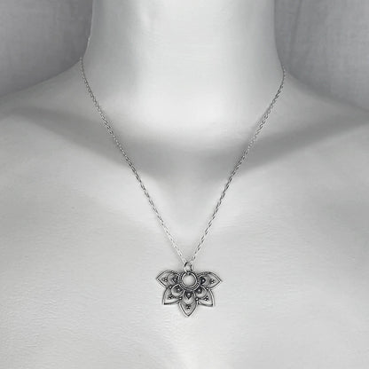 A woman wearing a sterling silver chain necklace with a trendy openwork half mandala  small charm.