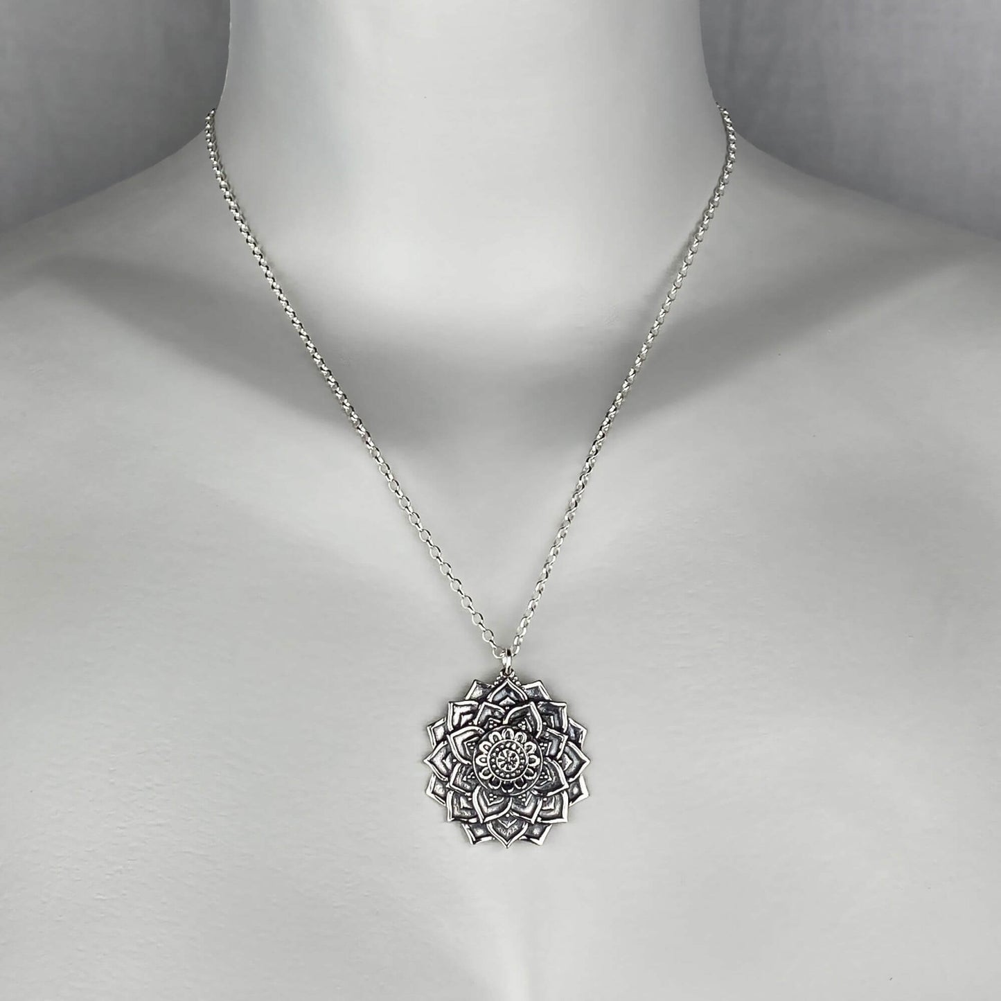 A woman model wearing a sterling silver chain necklace with a trendy large mandala flower pendant. Yoga jewelry.