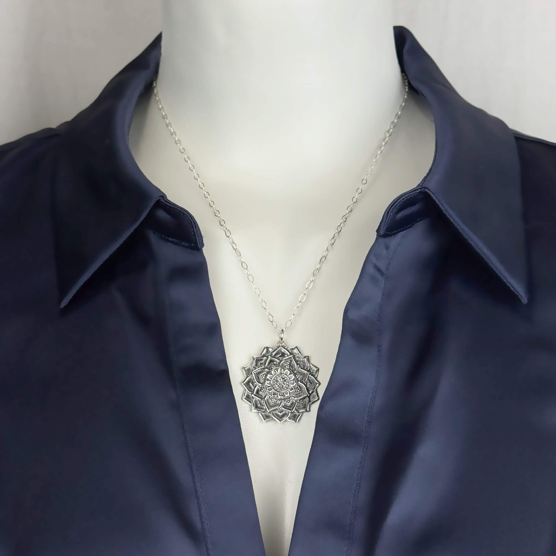 A woman model wearing a sterling silver chain necklace with a trendy large mandala flower pendant. Yoga jewelry.