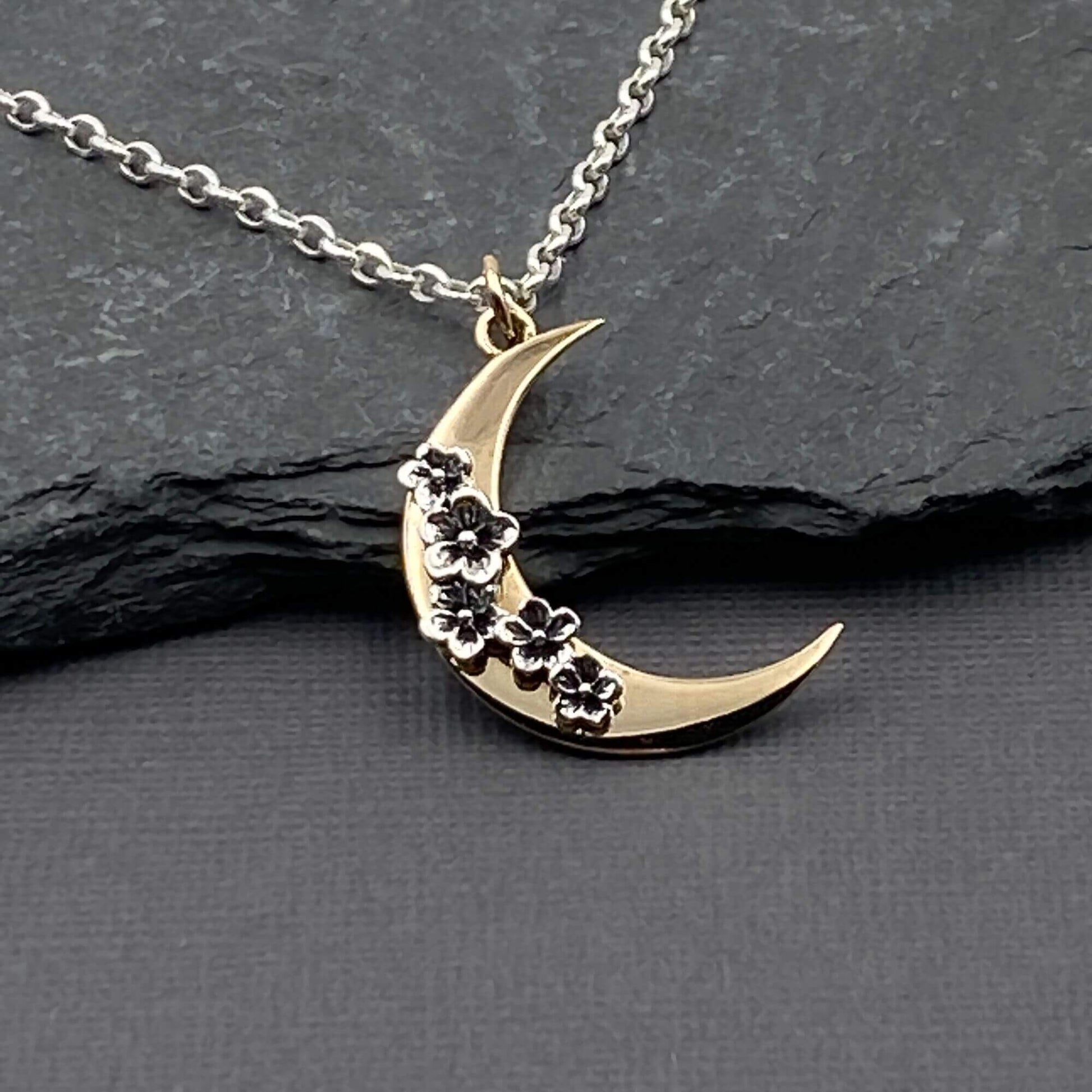 mixed metal bronze gold and sterling silver, gold moon shaped pendant with  silver cherry blossom flowers pendant on a sterling silver chain.