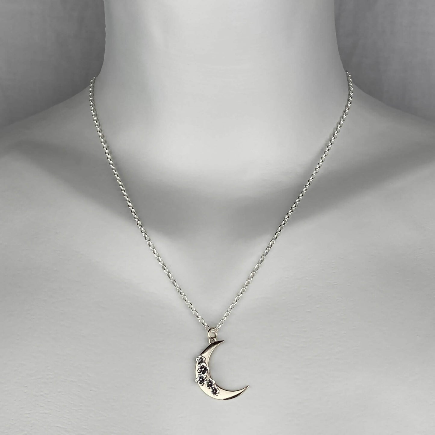 A woman wearing a sterling silver chain necklace with a trendy crescent moon  pendant in mixed metal gold and silver colors.