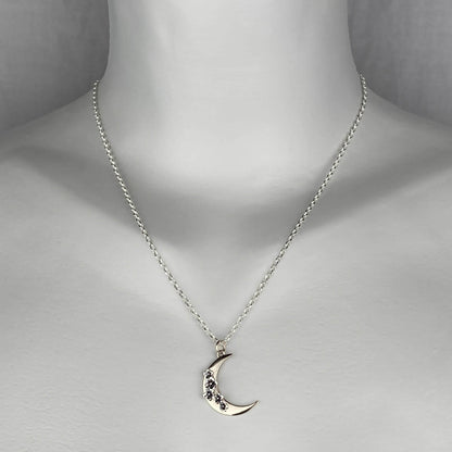 A woman wearing a sterling silver chain necklace with a trendy crescent moon  pendant in mixed metal gold and silver colors.