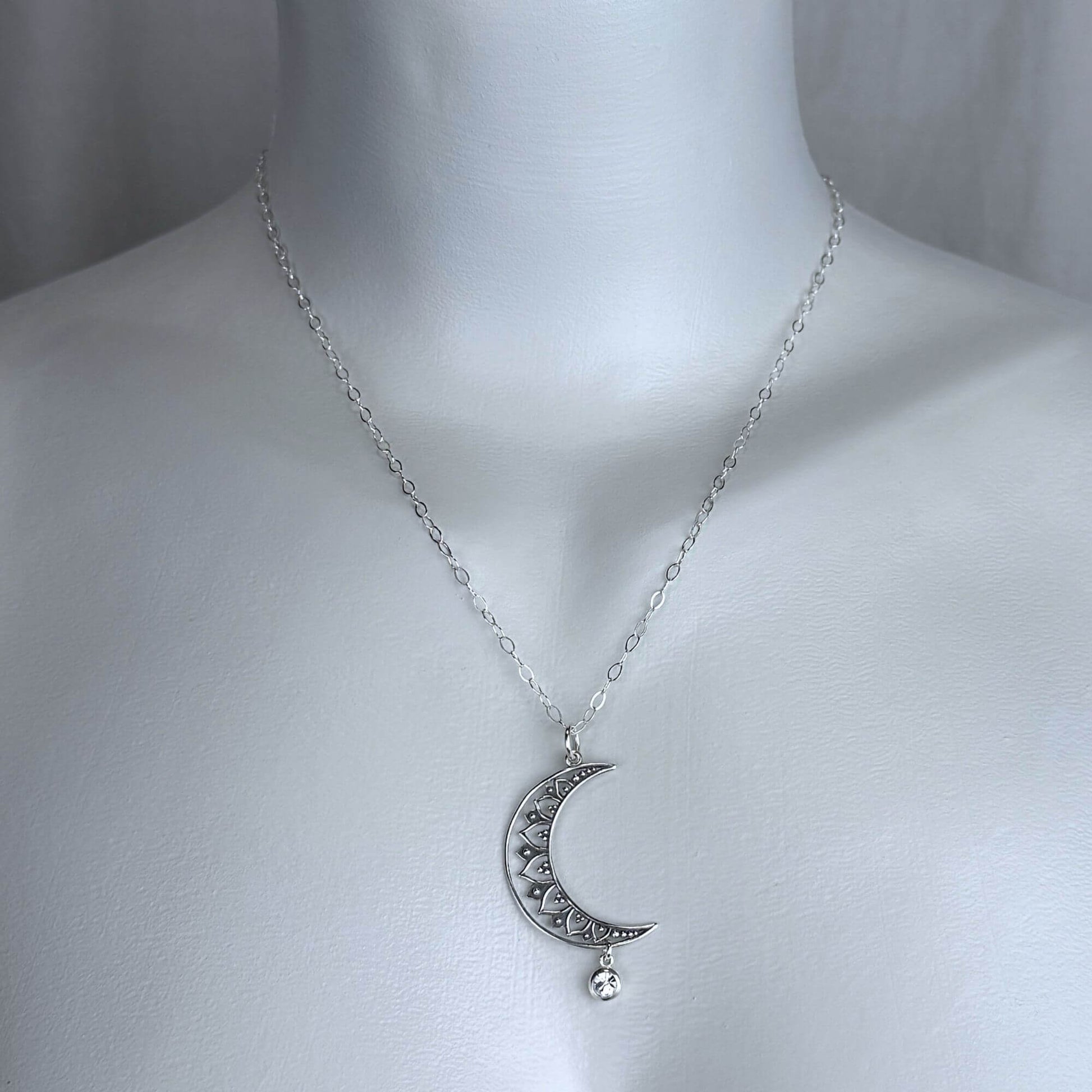 Model of a female wearing our Moon and Star necklace, featuring a large moon pendant on a silver cable chain.