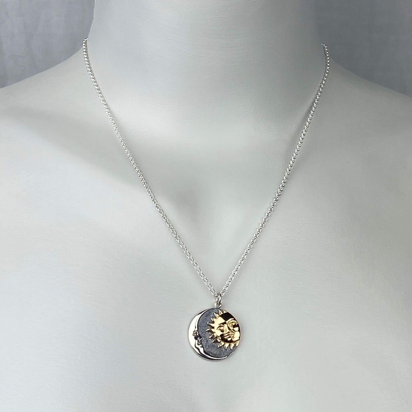 A woman wearing a sterling silver chain necklace with a trendy moon and sun in a round coin with gold and silver  pendant.