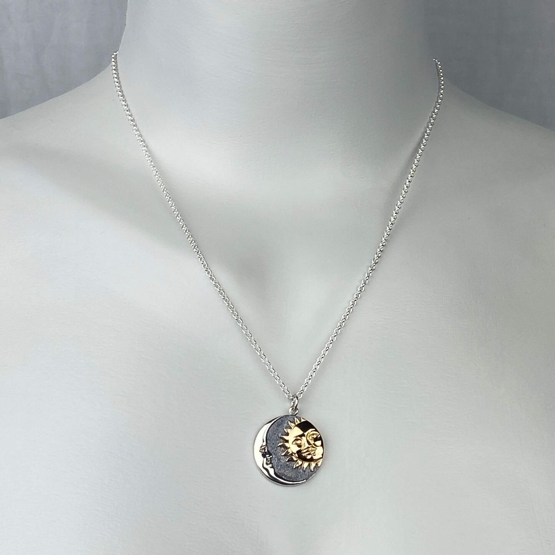 A woman wearing a sterling silver chain necklace with a trendy moon and sun in a round coin with gold and silver  pendant.