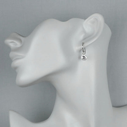 Model of a woman wearing petite minimalist silver Om dangle earrings.