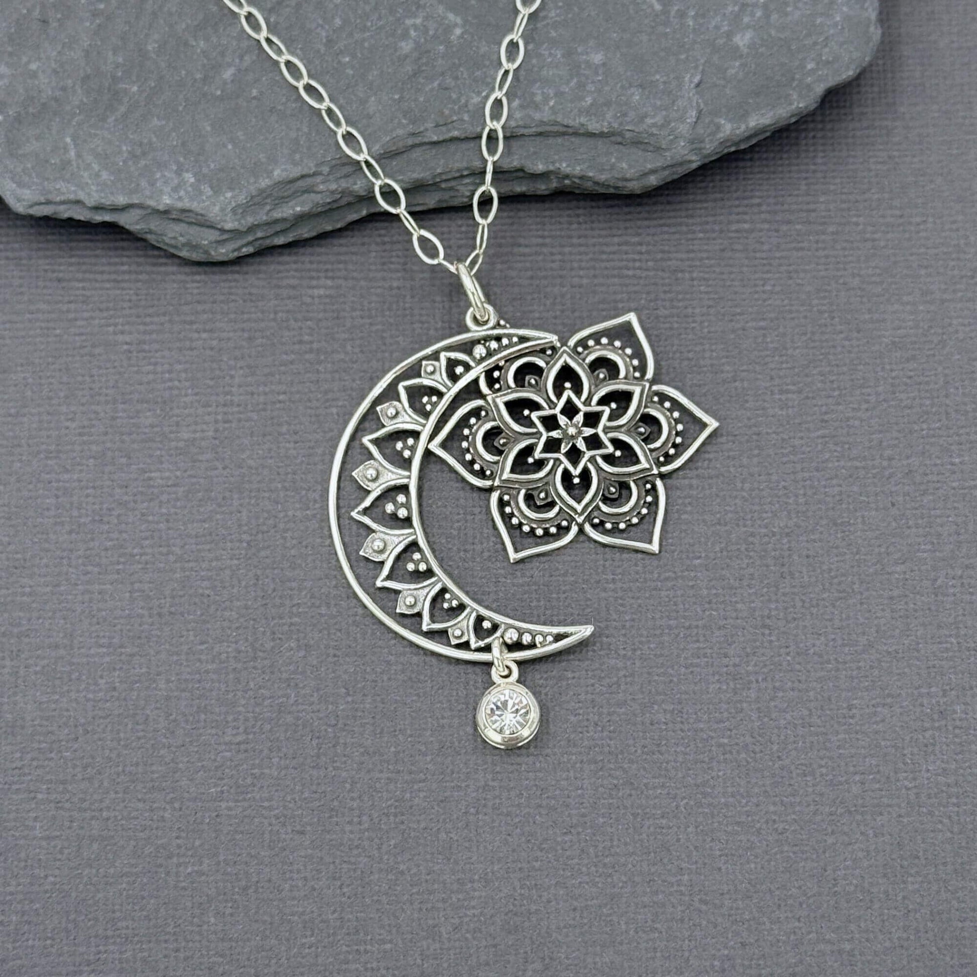 CLose up of sterling silver moon, sun and star pendant showing they dangle independently of each other. The pendant is on a sterling silver cable chain. 