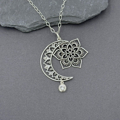 CLose up of sterling silver moon, sun and star pendant showing they dangle independently of each other. The pendant is on a sterling silver cable chain. 