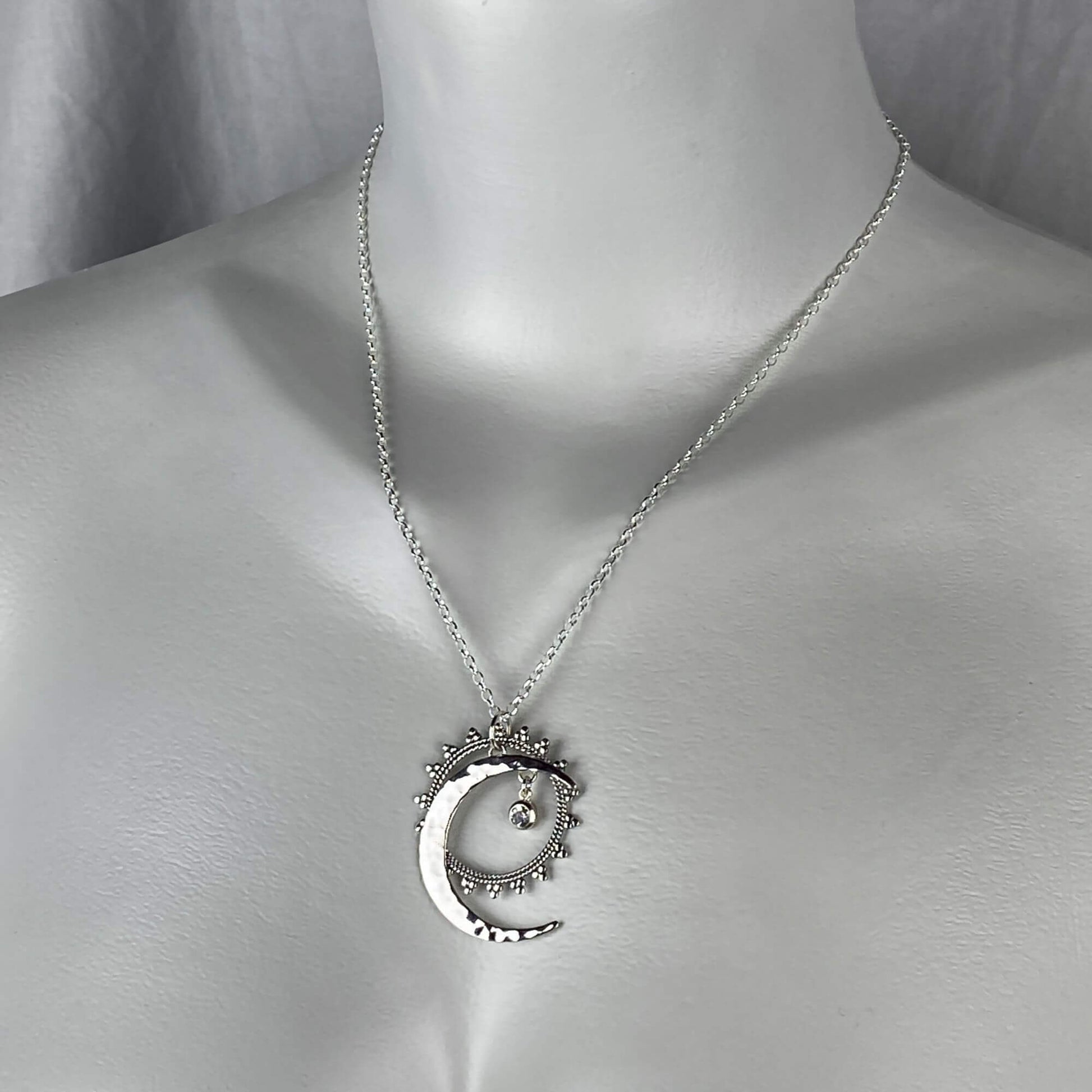 A woman model wearing a sterling silver sun, moon and stars celestial necklace.