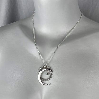 A woman model wearing a sterling silver sun, moon and stars celestial necklace.