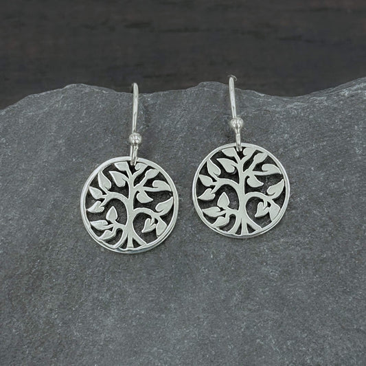 Close up view of 925 solid sterling silver earrings dangling from hook earwires with small circular Tree of Life charms with an openwork cut out design.  The tree charms are 5/8" tall and dangle freely.  A perfect jewelry gift for nature lovers.